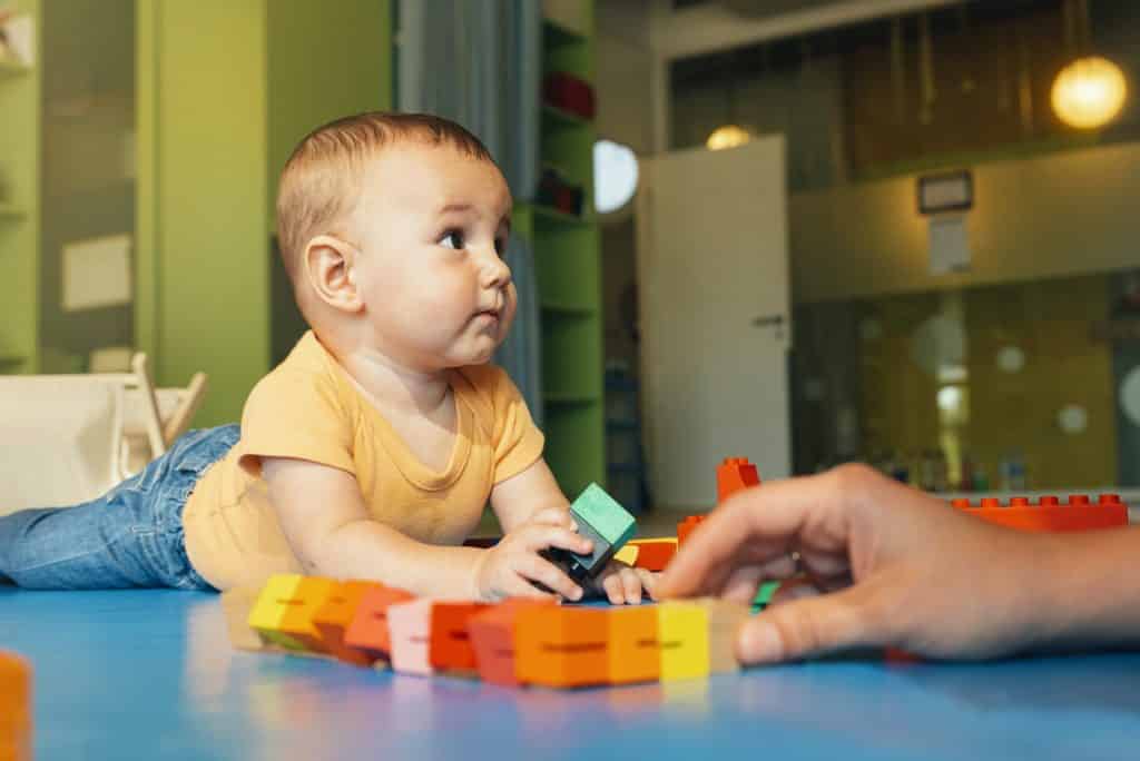 Happy baby playing with toy blocks.