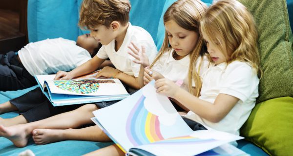 Group of Diverse Young Students Reading Children Story Book Toge