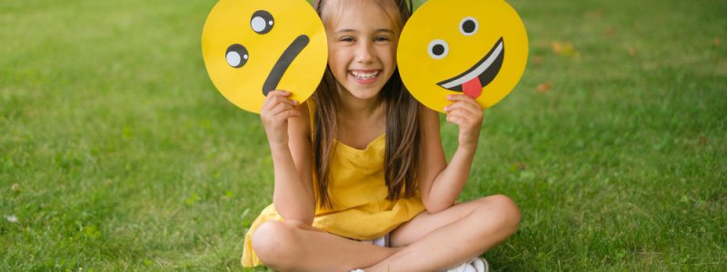 laughing-cheerful-child-holds-two-emoticons-hands